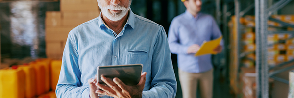 Older man using a tablet in a warehouse environment